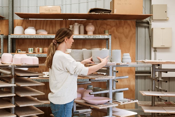 A woman holding on to a ceramic waiting to be put in the kiln.