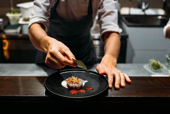 Chef plating up a dish at 50-50.