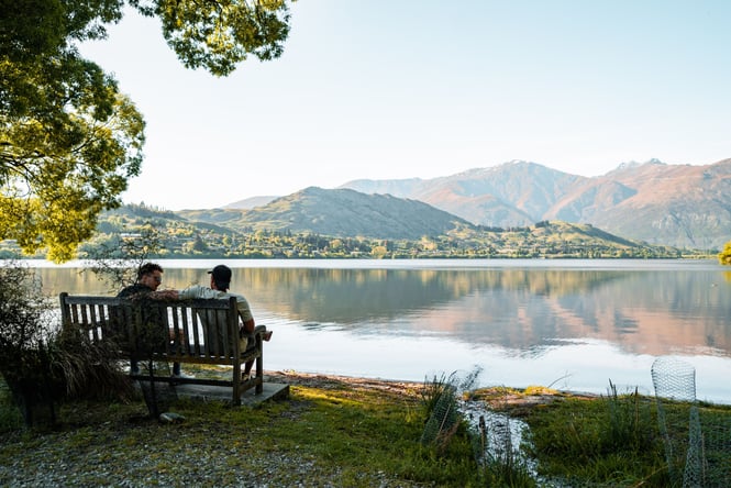 Two people sitting on a bench by a lake.