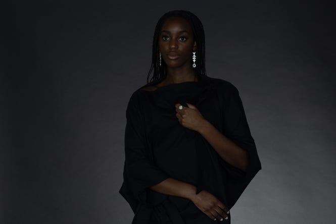 A woman in front of a black background wearing silver earrings.