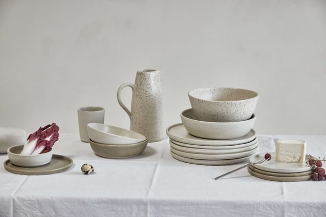 Salad Days ceramic bowls and plates on a table with a white table cloth.