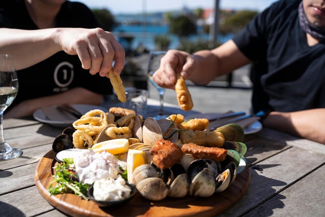 Hands reaching for food on a platter.