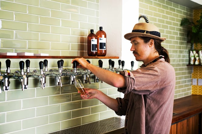 A close up of a man pouring a glass of beer.