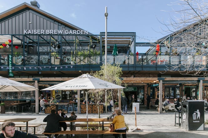 Exterior of Riverside Market with people sitting on tables outside in the sun
