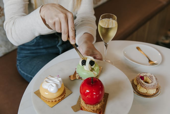 A hand cutting into a green dessert on a white table.