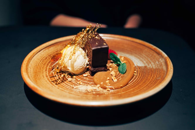 A chocolate cake decorated with cream and caramel.