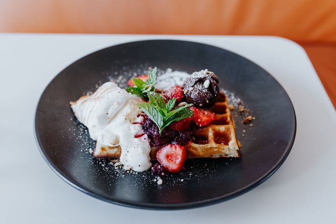 Fruit and cream on a plate of waffles.