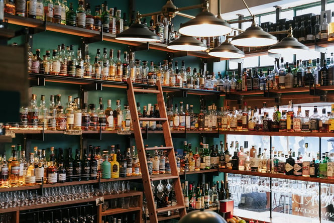Rows of whiskey shelves and a ladder at The Last Word.