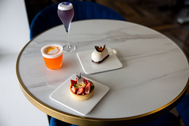 Plates of food and cocktails on a white table.