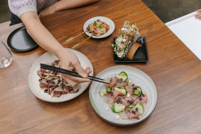 Person using chopsticks to pick up piece of Sashimi at Bar Yoku in Christchurch