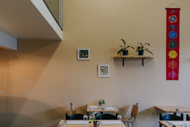 Tables and chais up against a yellow wall.