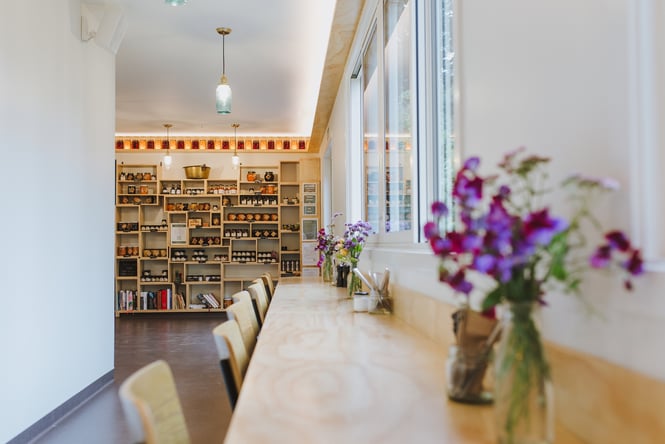Window seating area with shelves full of Augustines of Central products at the shop area in the background