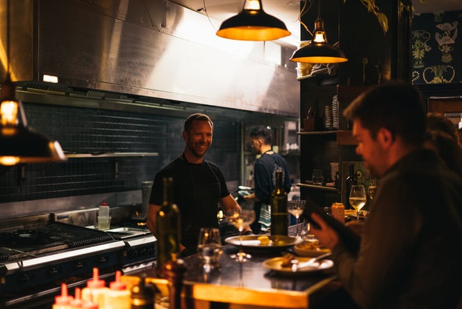 Staff working in the kitchen in a darkly lit 5th Street restaurant.