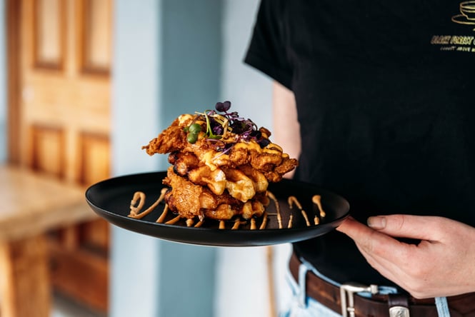 Hands holding a plate of savoury waffles.