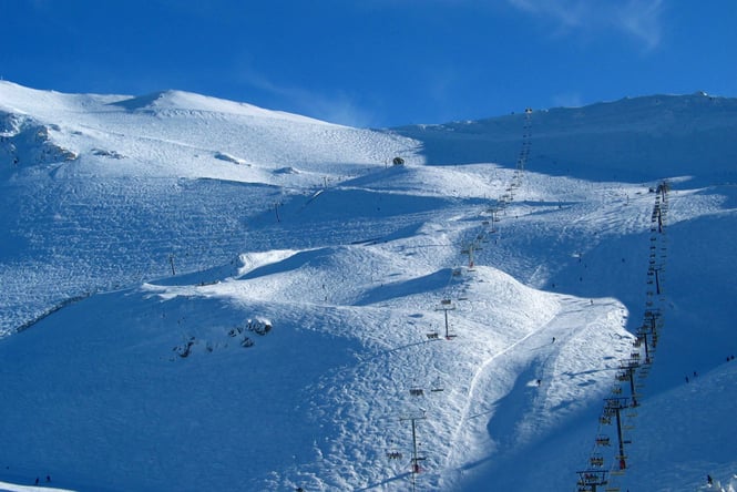 Skiiers on snowy slopes on a sunny day.
