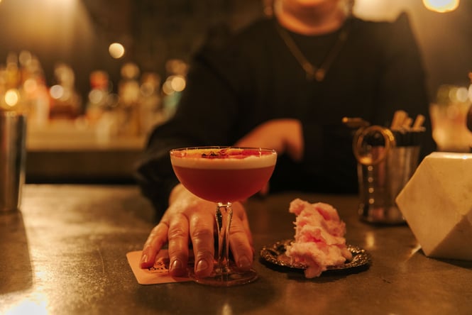 Bartender pushing cocktail forward on bar counter at Tiger Baby Bar