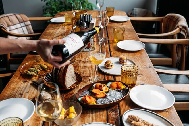 Table full of food and someone pouring wine at Muttonbird in Wanaka