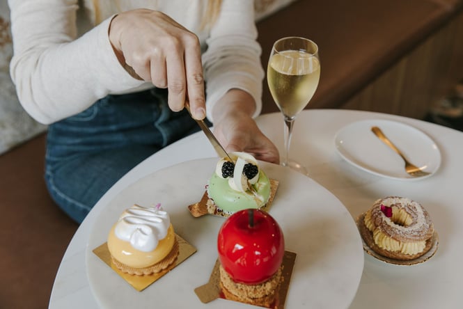 Close up of someone cutting into one of four beautiful patisserie dishes from Sweet Soul next to a glass of champagne