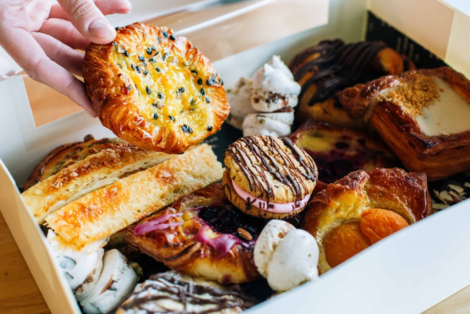 A box generously stuffed with baked goods including danishes and biscuits