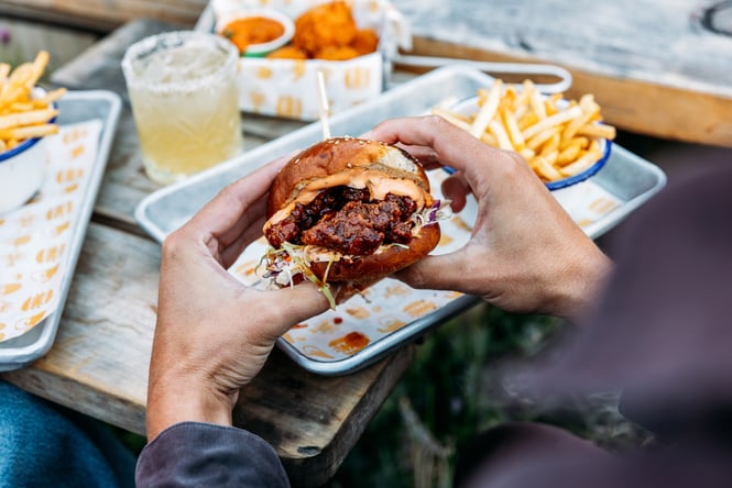 Hands holding a burger.