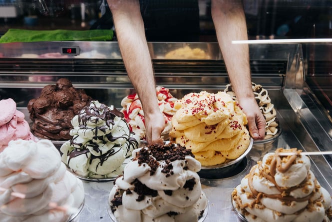 Hands placing a bowl of gelato into the counter at Rollickin' Gelato.