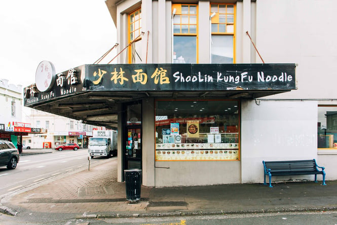 The grey and black entrance to Shaolin Kung Fu Noodle Bar on a grey day.
