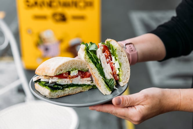 Hands holding a plate of sandwiches.