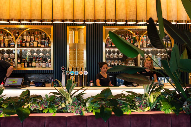 A staff member working at a brightly coloured bar.
