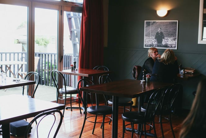 Two women sitting a blue painted cafe.