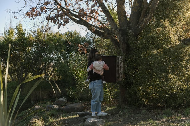 A woman and child looking at a sign in a bush.