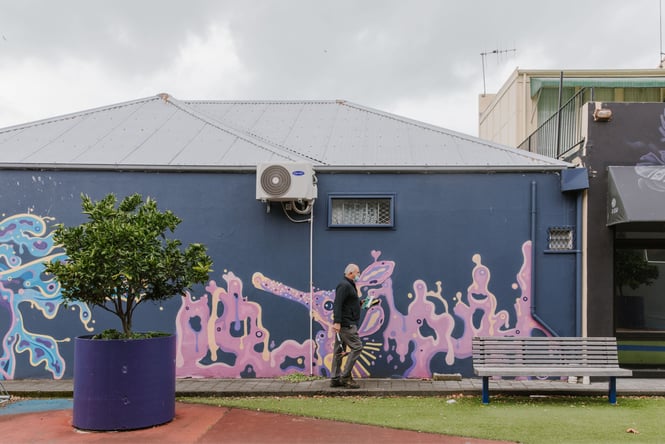 Art on an exterior wall with a man walking past.