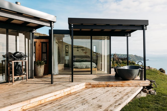 A view of a B&B on a hill top with the ocean in the background.