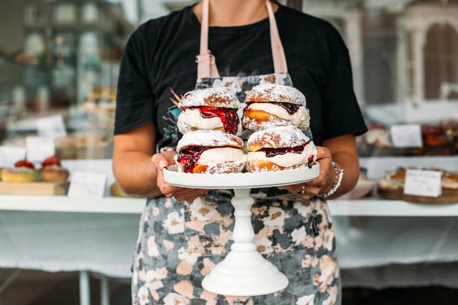 A baker holding a stand full of cream-filled brioche