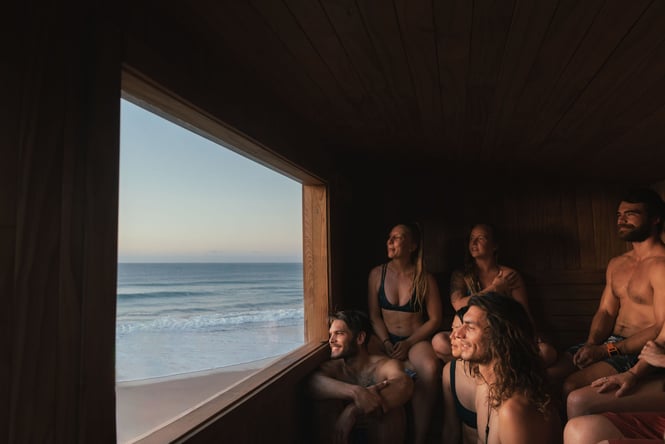 People in a sauna looking out to sea.