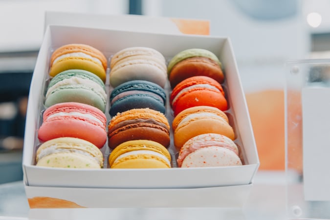 Brightly coloured macaroons in a white box.