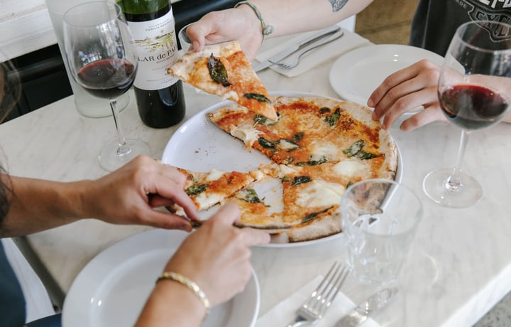 Diners enjoy a slice of pizza from one of the 10 best pizza spots in Christchurch.