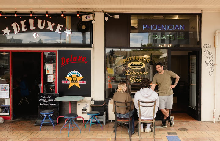 Customers sitting at an outdoor table outside Phoencian Falafel.
