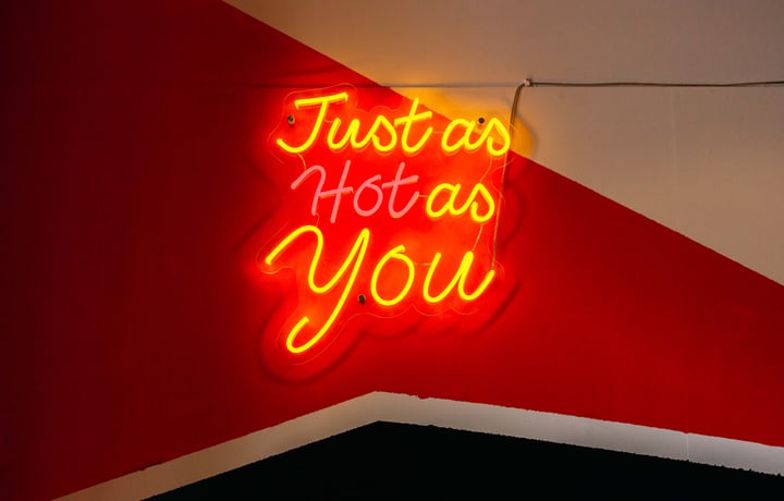 A fluorescent sign that says 'just as hot as you'.