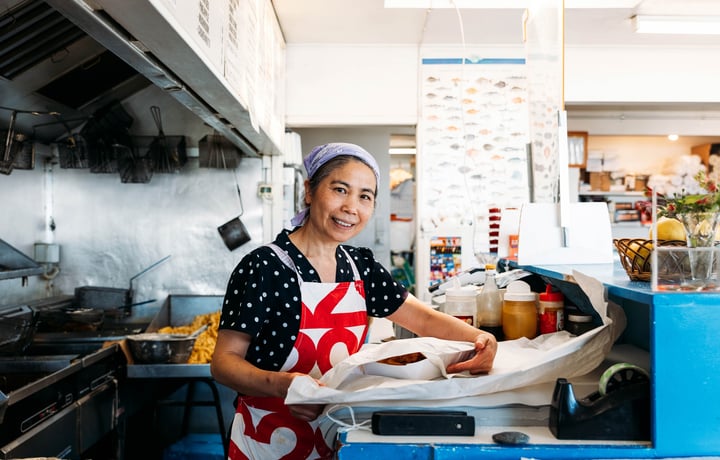 A woman packing fish and chips in a fish and chip shop.