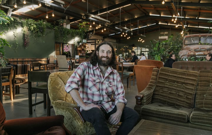 Chef Pedro Johnston sitting on couch smiling at Scoundrel in Christchurch