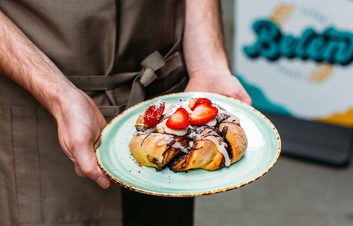 Two hands holding a vegan pastry on a plate.