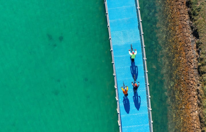 Three people biking on a bike trail over water.