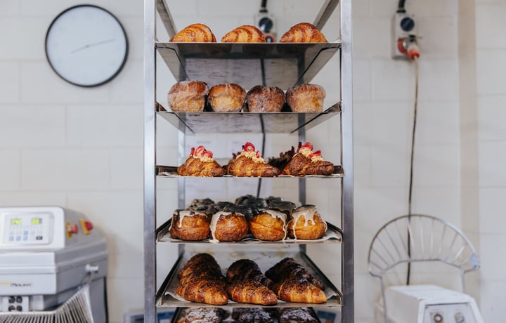 Silver trays of croissants and pastries stacked on top of each other in bakery kitchen