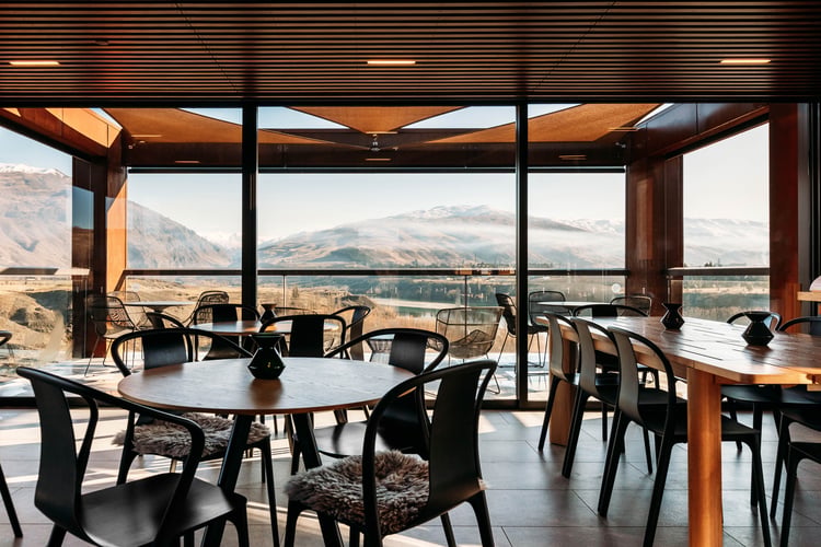 Tables and chairs in a restaurant looking out to a lake.