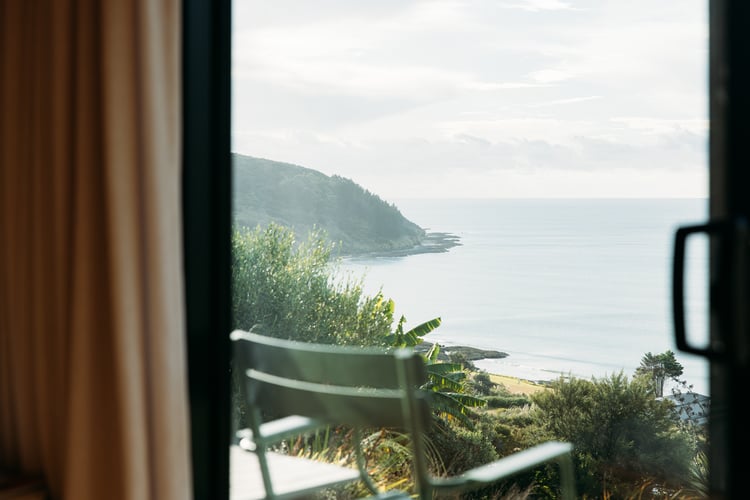 The view of the ocean from inside a house on a hill.