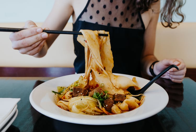 A woman eating a bowl of noodles at Miss Peppercorn in Christchurch.