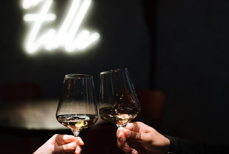 Close up of two hands clinking wine glasses.