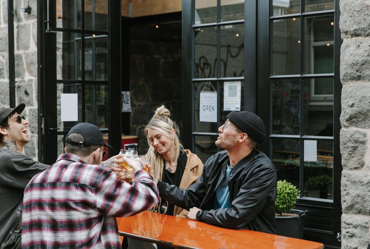 A group of people sat around a table drinking beer at Steamer Basin, Dunedin.
