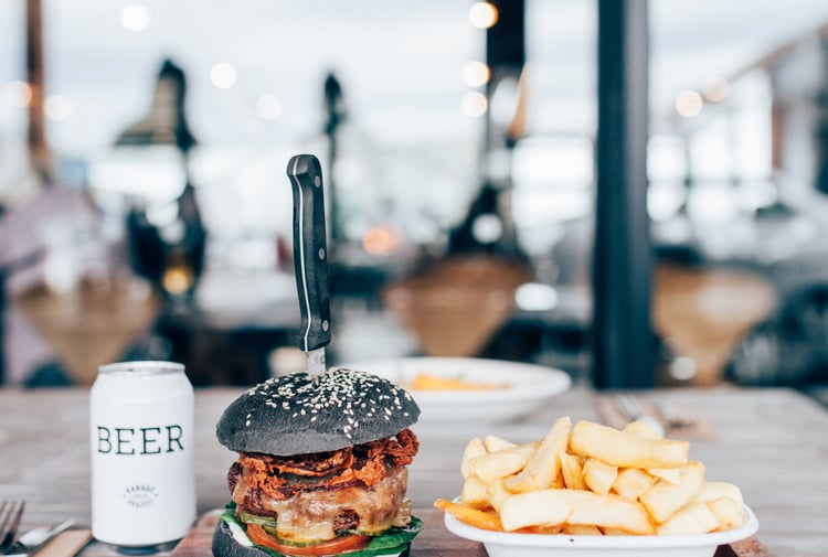 A burger, chips and beer sitting on a table in Ten27 Christchurch cafe.