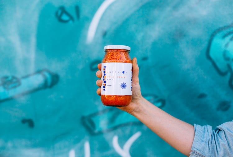 Jar of pickle against a blue wall.